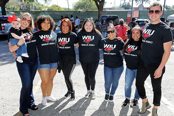 Seven cheer alumni in a group smiling at the camera