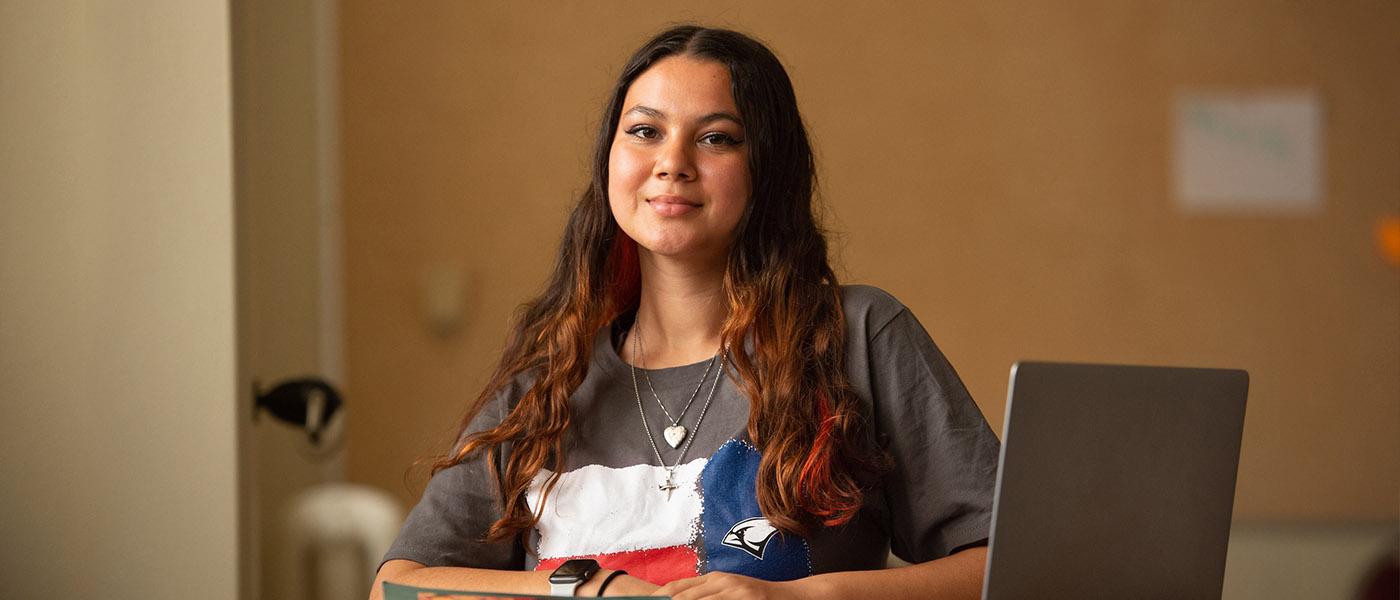 History student sitting at her desk with a book and laptop