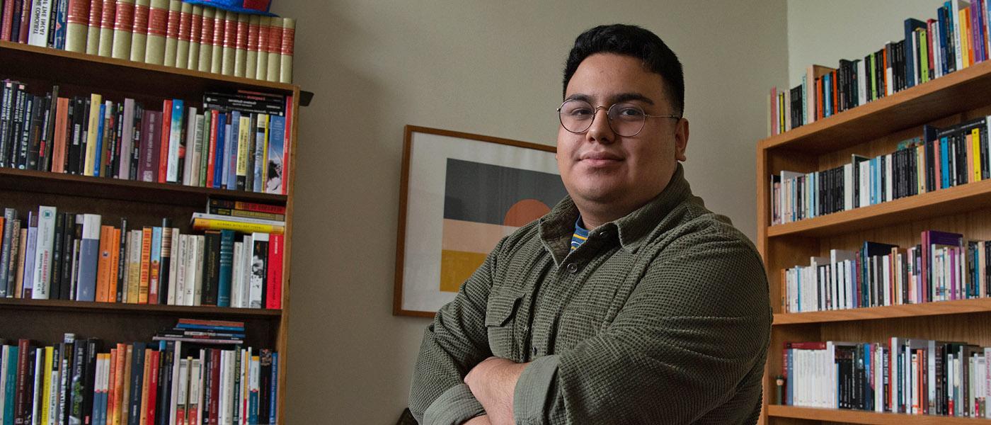 西班牙语 student with arms crossed standing in front of bookshelves filled with 西班牙语 文学