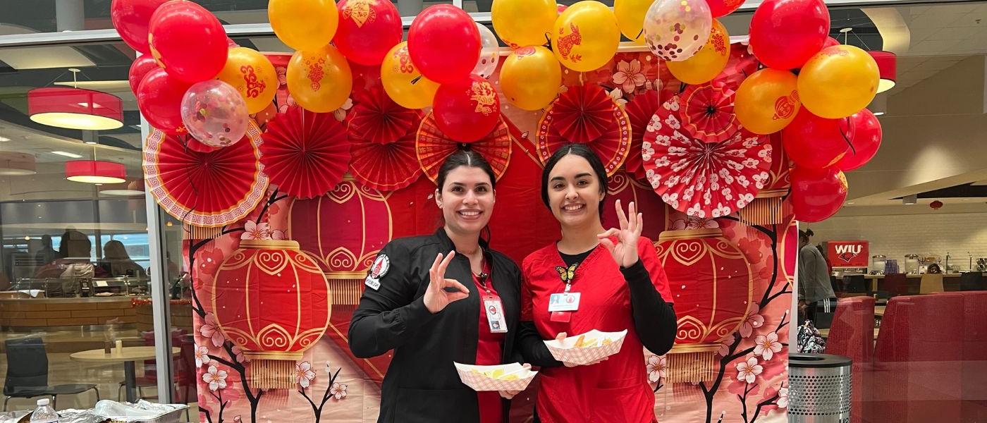 Two students posing in front of red lanterns