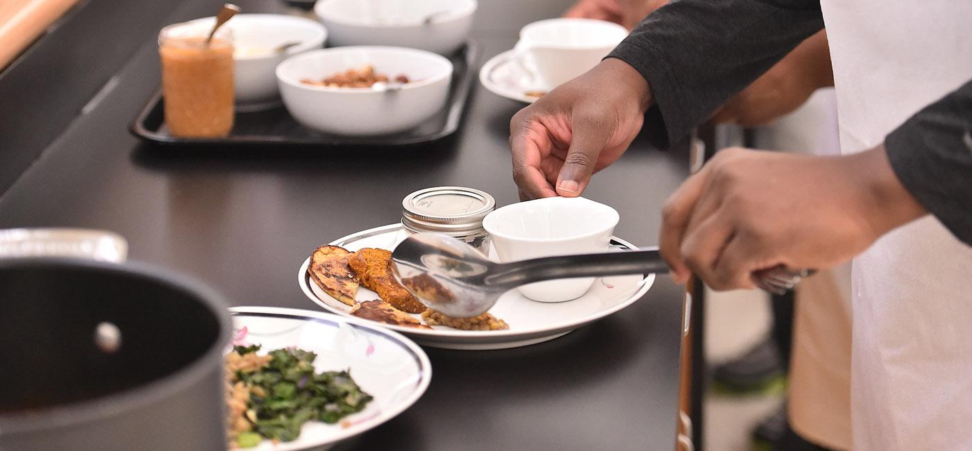 一个学生用手在盘子里准备食物的特写照片